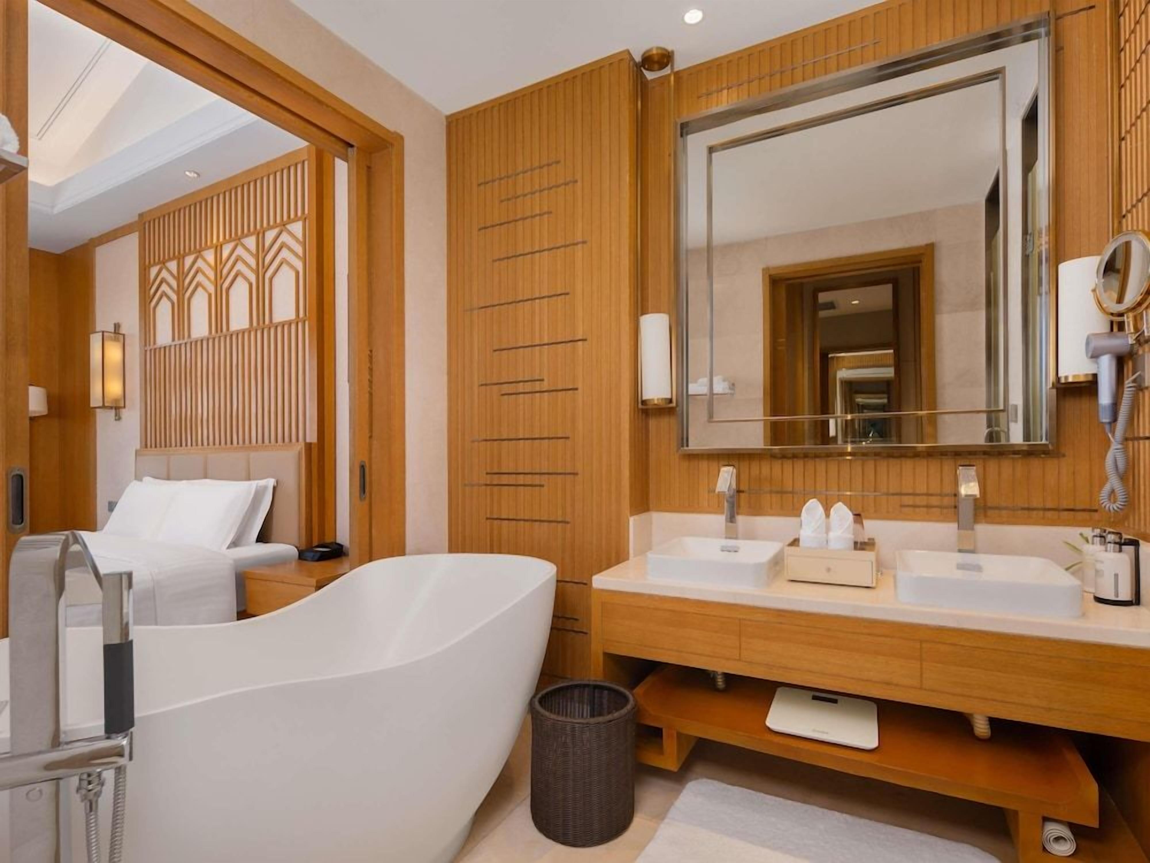 Ein modernes Badezimmer mit einer freistehenden Badewanne, einem Doppelwaschtisch und einem großen Spiegel.