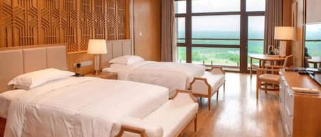 A hotel room with two beds, a desk, and a view of the landscape.