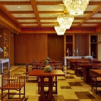 Un hall de hotel con paneles de madera, suelo de cuadros y varias mesas y sillas.