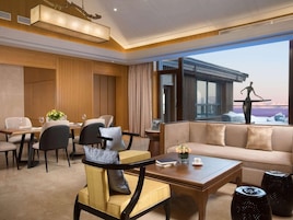 Habitación de hotel con comedor, sofá y vista panorámica de la ciudad.
