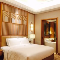 Una habitación de hotel con una cama grande, una mesita de noche, una lámpara de pared y un espejo.