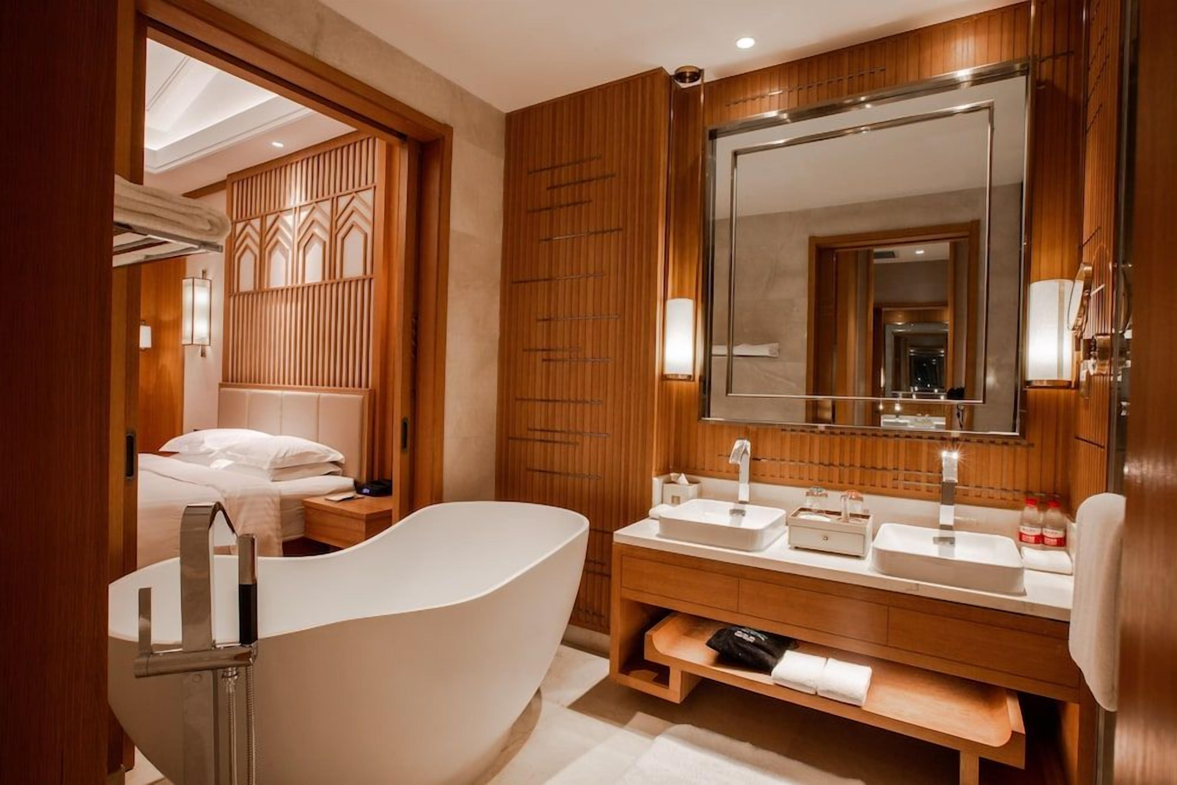 A modern bathroom with a freestanding bathtub, dual sinks, and a large mirror.