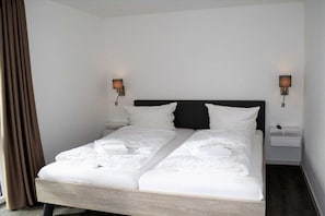 A hotel room with a double bed, two bedside tables, and two wall-mounted lamps. - House No. 23, Holiday Home Deichgraf (Wangerland)
