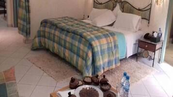A hotel room with a bed, a bedside table, a nightstand, a tray with food, and a water bottle.