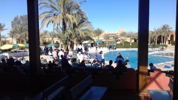 An outdoor seating area with a pool and palm trees.
