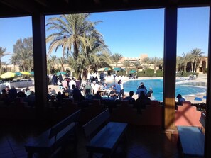 An outdoor seating area with a pool and palm trees. - Belere (Aarab Sebbah Ziz)