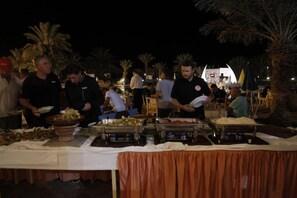 A buffet setup with multiple food stations and attendees. - Belere (Aarab Sebbah Ziz)