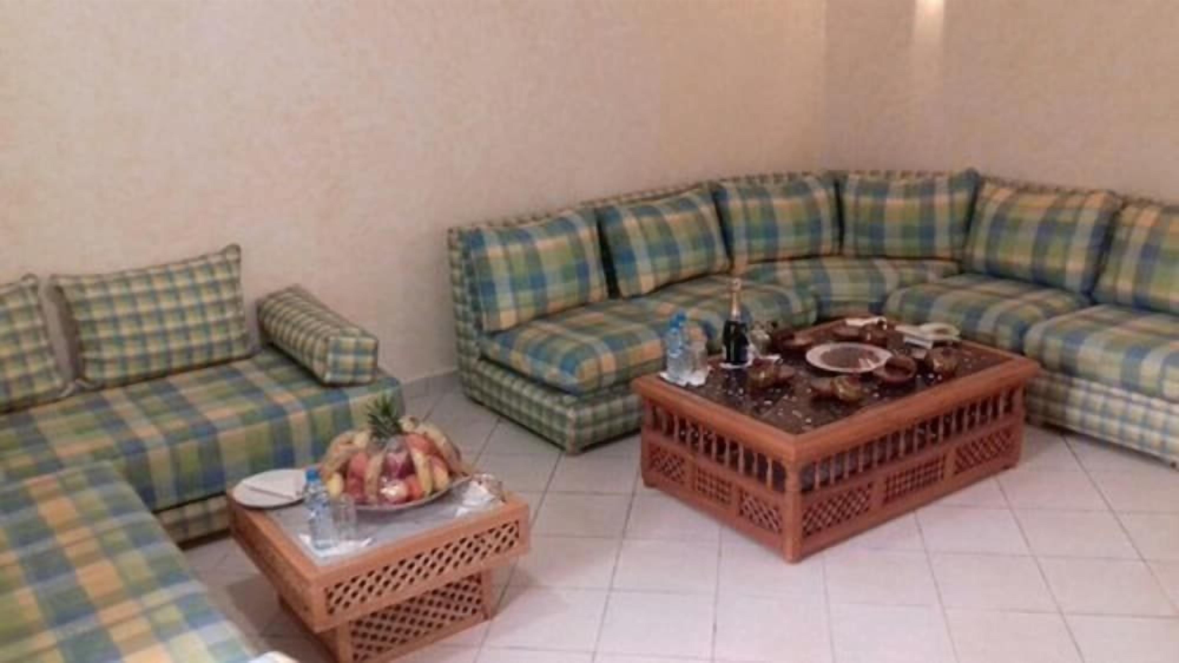 A living room with a sectional sofa, a coffee table, and a side table with fruits and drinks.