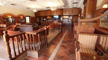 A hotel lobby with a bar area, seating arrangements, and a staircase.