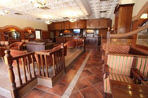 A hotel lobby with a bar area, seating arrangements, and a staircase. - Belere (Aarab Sebbah Ziz)