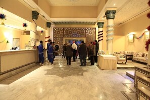 A hotel lobby with marble flooring, a reception desk, and a seating area with sofas. - Belere (Aarab Sebbah Ziz)