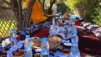 Un espace de restauration en plein air, avec une table dressée pour un repas, entouré d’arbres et agrémenté d’un hamac.