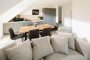 Une cuisine moderne avec un coin repas, des meubles gris et une table en bois.