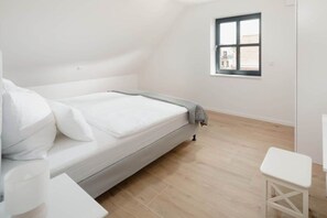 Ein Schlafzimmer mit einem Einzelbett, einem kleinen Tisch, einem Fenster und Blick nach draußen.