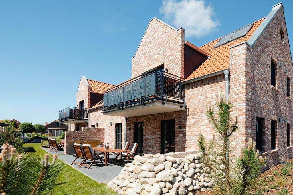 Een modern huis van baksteen met een balkon, een terras en een stenen muur.