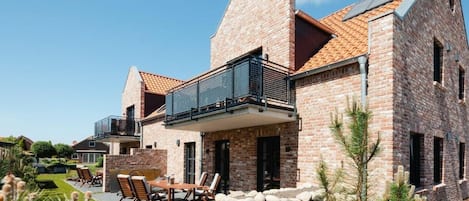 Een modern huis van baksteen met een balkon, een terras en een stenen muur.