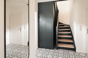Un escalier avec un mur sombre et des marches en bois menant à une porte blanche.