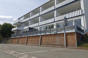 Een meerhoog gebouw met balkons, een overdekte ingang en een parkeerplaats.