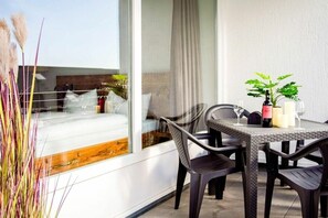 A balcony with wicker furniture, a potted plant, and a bottle of wine. - Holiday apartment 605 (Winterberg)