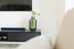A room with a black console table, a green vase with flowers, and a black object on the table. - Coastal Suite North | Directly on the waterfront (Greetsiel)