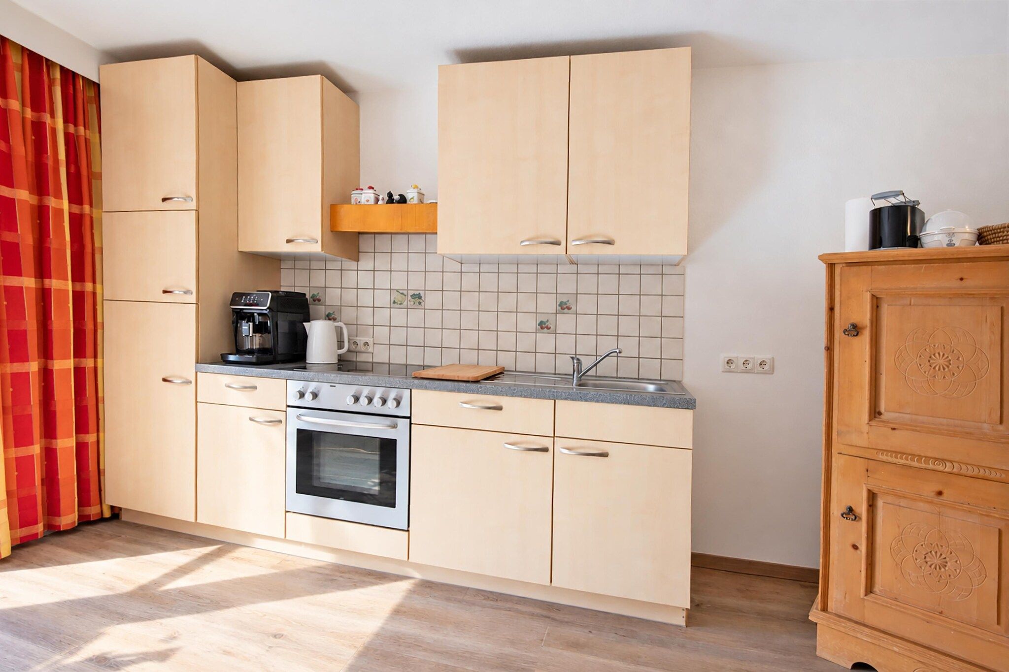 A compact kitchen with light-colored cabinets, a built-in oven, a coffee maker, and a sink.