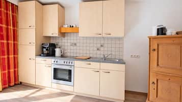 A compact kitchen with light-colored cabinets, a built-in oven, a coffee maker, and a sink.
