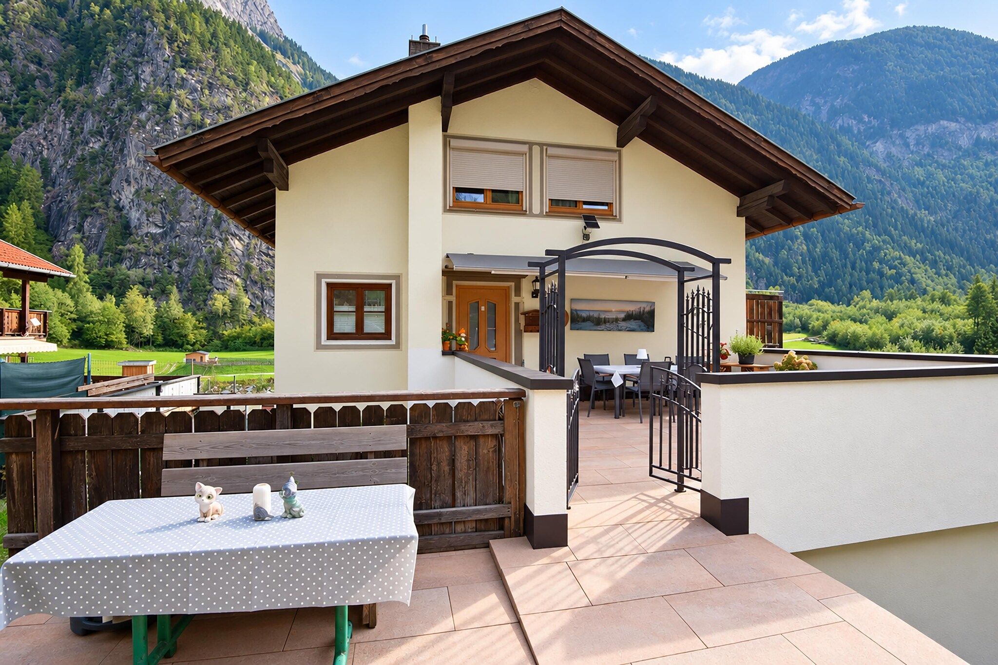 Un chalet doté d’une terrasse, d’une table à manger et offrant une vue sur les montagnes.
