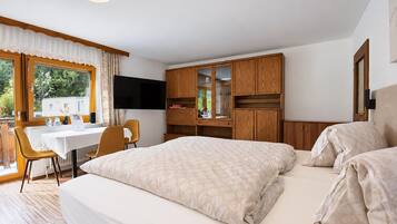 Ett hotellrum med en säng, ett skrivbord, en stol, en tv och en garderob.