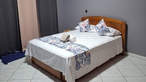 Una habitación de hotel con cama, cortinas y piso de baldosas.