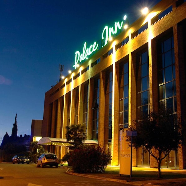 Un hotel con un cartel llamativo que dice 'Palace Inn' y una fachada grande y moderna con múltiples ventanas.