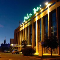 Un hotel con un cartel llamativo que dice 'Palace Inn' y una fachada grande y moderna con múltiples ventanas.