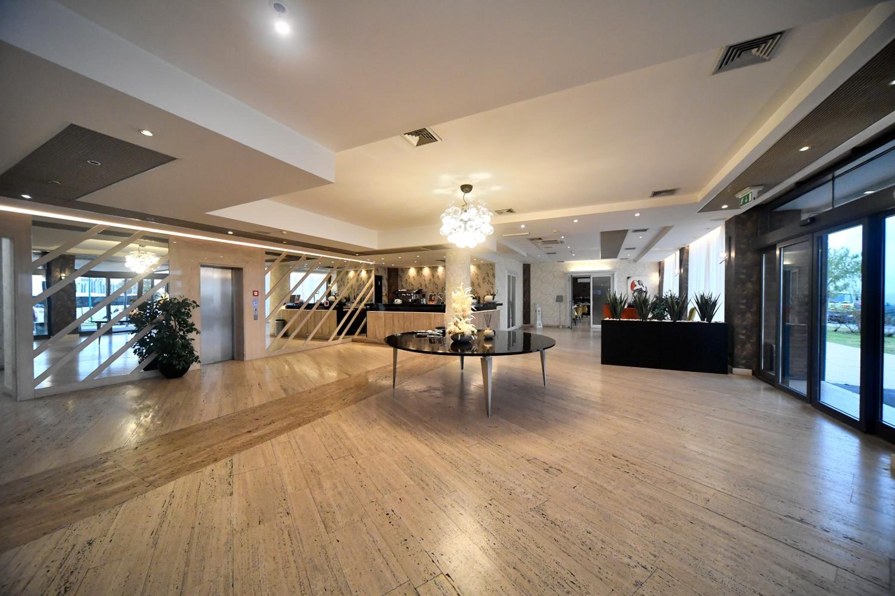 Eine geräumige Lobby mit einem runden Tisch in der Mitte, einer Treppe und einem großen Fenster.