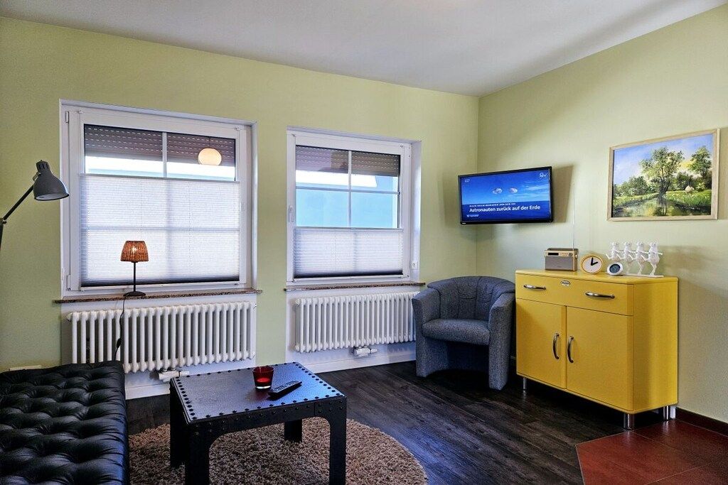 Ein Wohnzimmer mit einer Couch, einem Couchtisch, einem Fernseher und einem gelben Schrank.