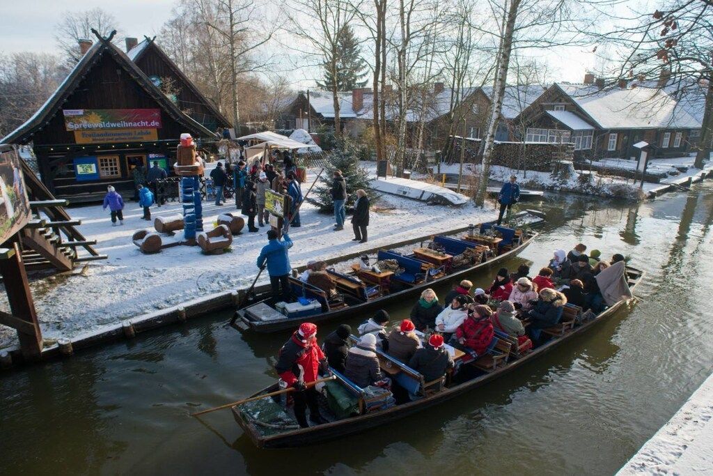 A traditional wooden building with a sign, a dock with a boat, and a snowy landscape.