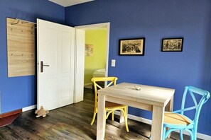 A room with a wooden door, a table with chairs, and two framed pictures on the wall. - Holiday apartment with 1 bedroom (Lübbenau\/Spreewald)