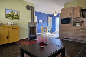 A modern living room with a fireplace, a yellow cabinet, a dining area, and a kitchen with wooden cabinets. - Holiday apartment with 1 bedroom (Lübbenau\/Spreewald)