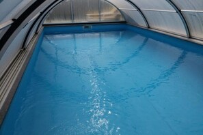 Een binnenzwembad met helder water, omgeven door een metalen constructie.