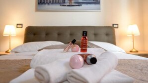 A neatly made bed with towels, a bottle of lotion, and a perfume bottle.