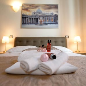 A neatly made bed with towels, a bottle of lotion, and a perfume bottle.