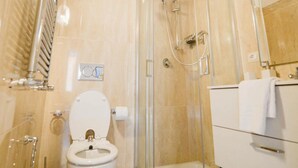 A bathroom with a glass-enclosed shower, a toilet, and a vanity with a mirror.