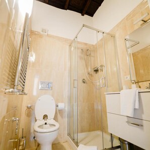 A bathroom with a glass-enclosed shower, a toilet, and a vanity with a mirror.
