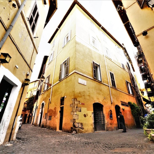 A narrow cobblestone street flanked by buildings with arched doorways and windows.