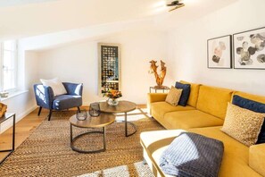 A living room with a sofa, armchair, coffee table, and a bookshelf. - 3 (Sun deck) in Villa Fabiola (Ostseebad Binz)