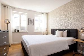 A bedroom with a bed, bedside tables, a wardrobe, and a window with curtains. - 3 (Sun deck) in Villa Fabiola (Ostseebad Binz)