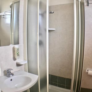A bathroom with a sink, mirror, and shower. - Hotel Tritone (Rimini)
