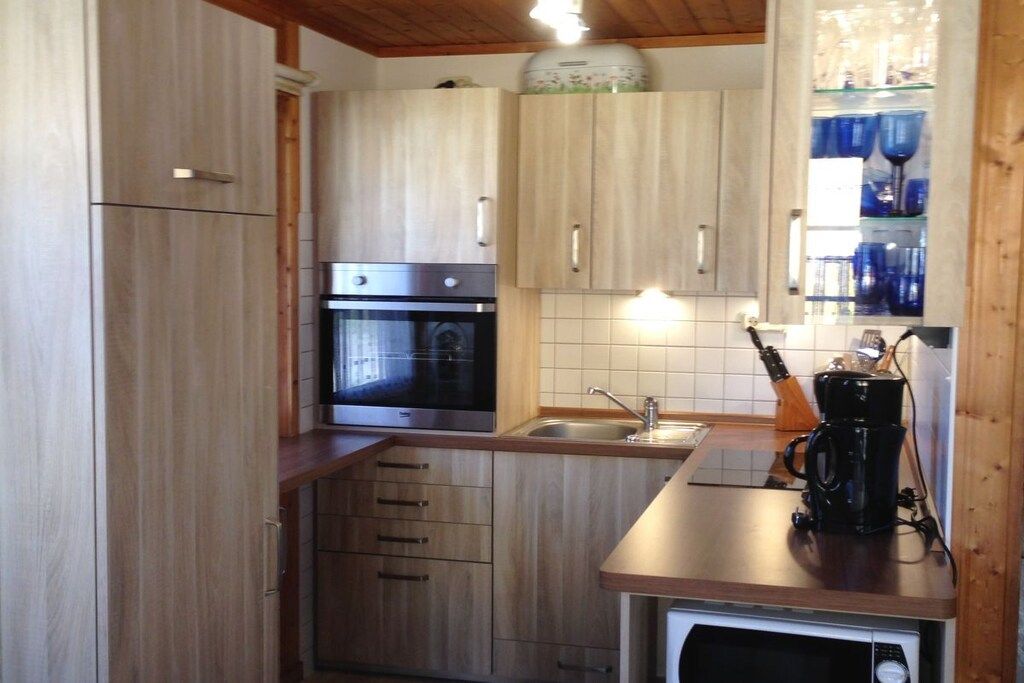 A kitchen with wooden cabinets, a stainless steel oven, a coffee maker, and a sink.