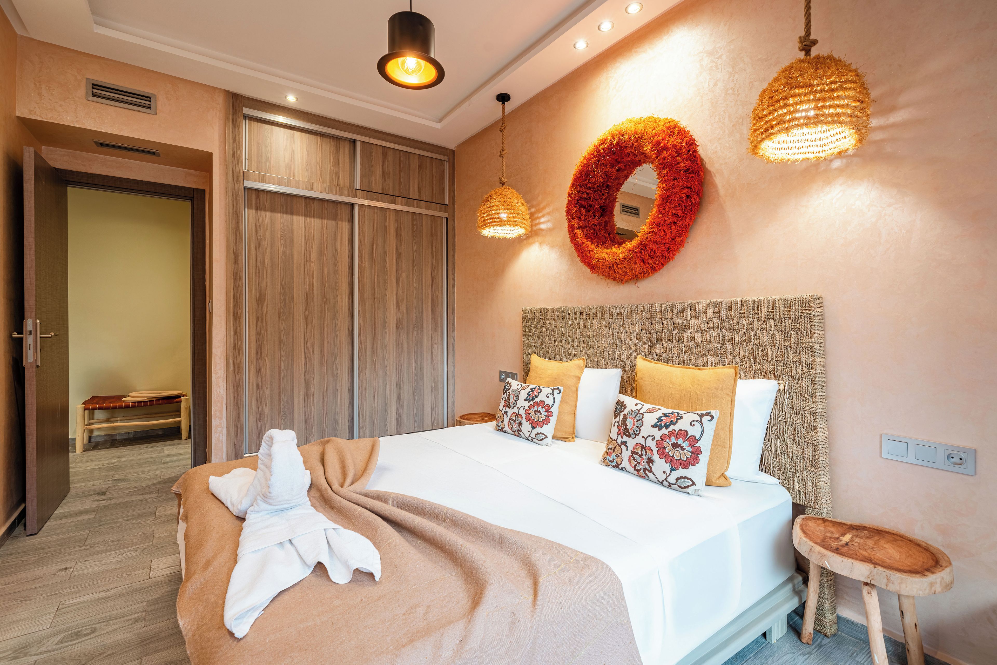 A hotel room with a bed, bedside table, and a mirror on the wall.