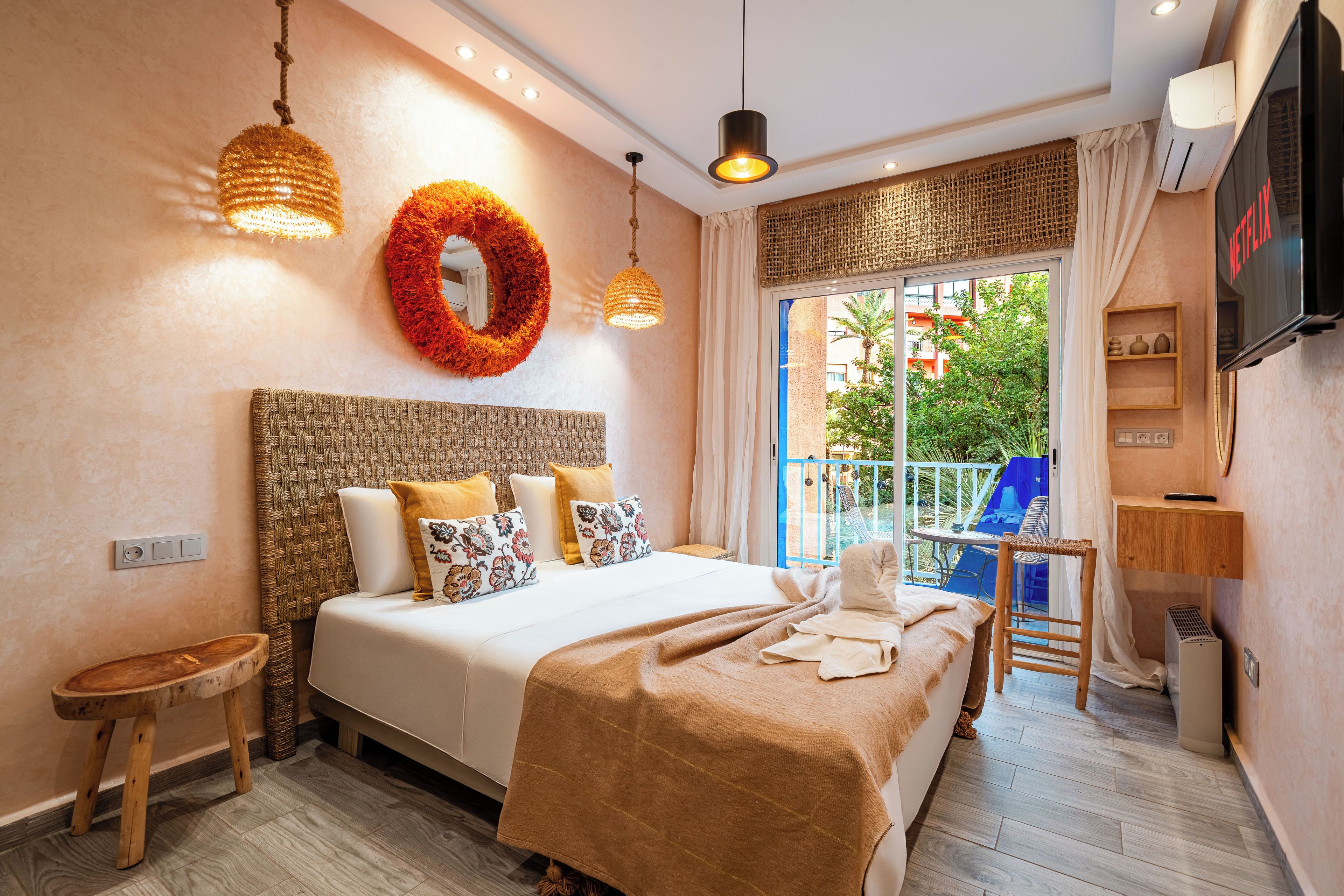 A modern hotel room with a large bed, a TV, and a balcony with a view of the city.