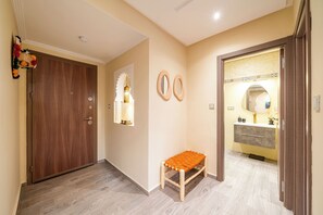 Un pasillo con una puerta de madera, un banco y un espejo en la pared.