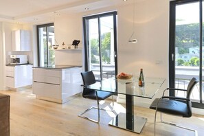 A modern kitchen with a glass dining table, two chairs, and a view of the outdoors. - Baltic Cloud at Villa Augustine (Ostseebad Binz)